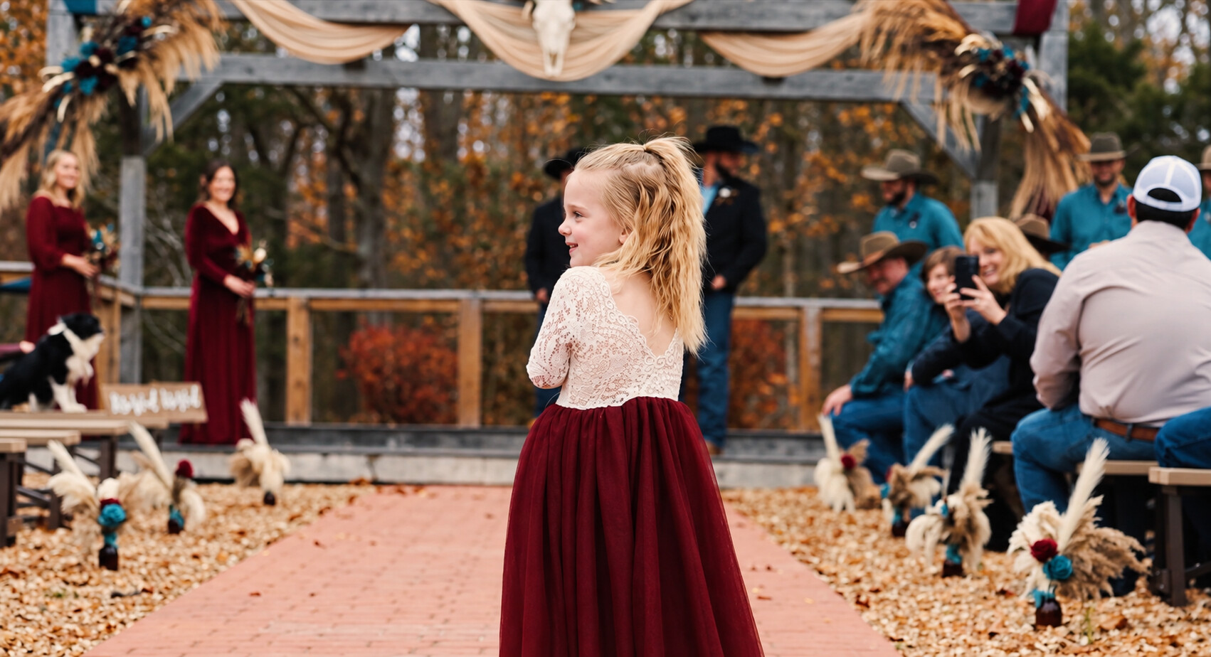 A young flower girl walking down Heather and Chase's autumn wedding aisle