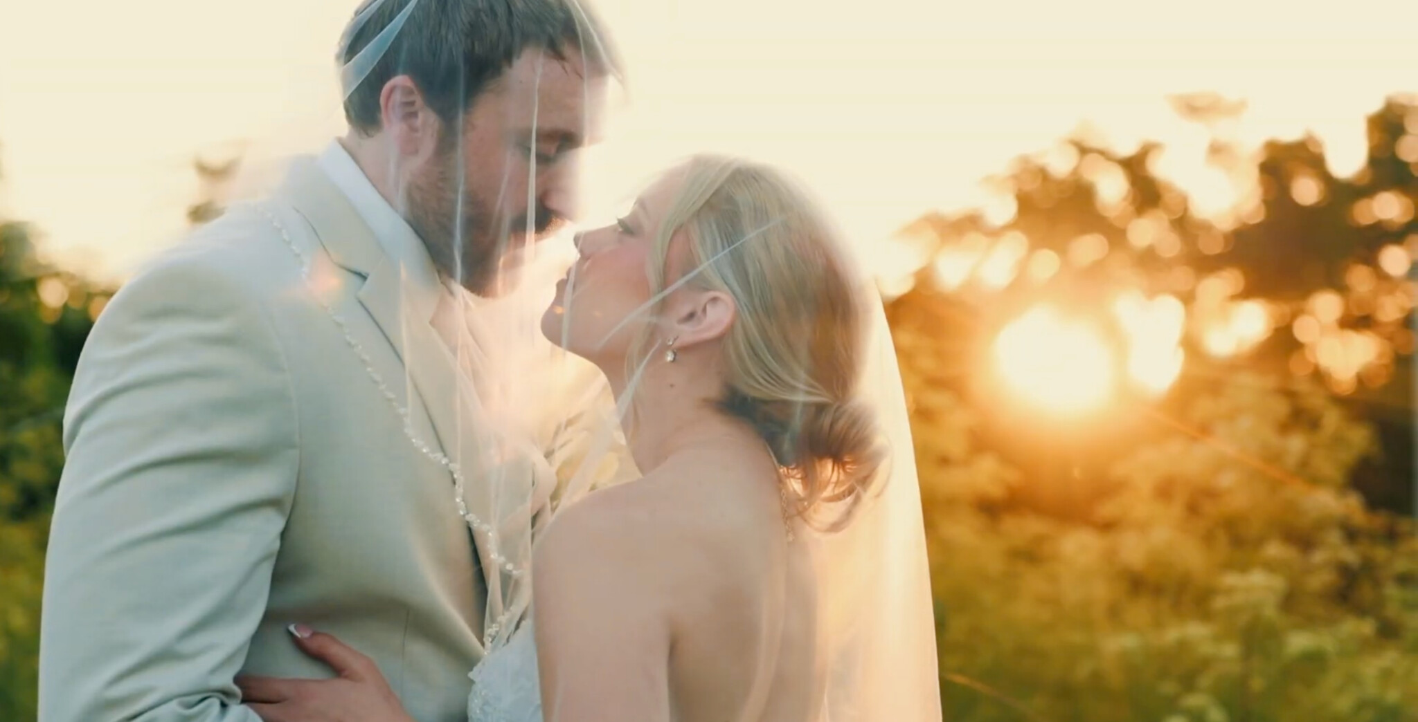 Karstin and Logan sharing a quiet moment beneath her veil at sunset